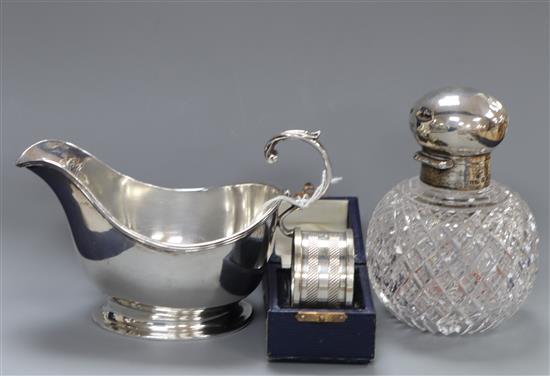 A George V silver sauceboat, a late Victorian silver mounted glass scent bottle and a cased silver napkin ring.